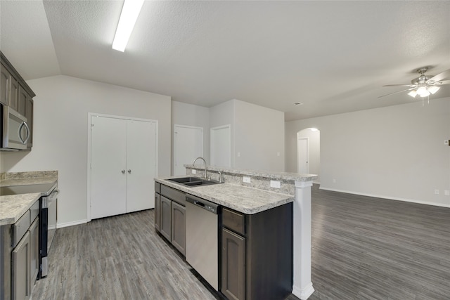 kitchen featuring appliances with stainless steel finishes, a textured ceiling, an island with sink, and sink