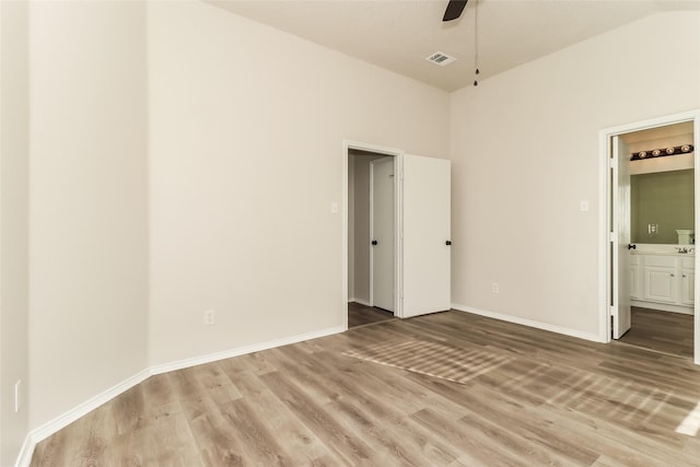 unfurnished bedroom with ceiling fan, ensuite bath, and wood-type flooring