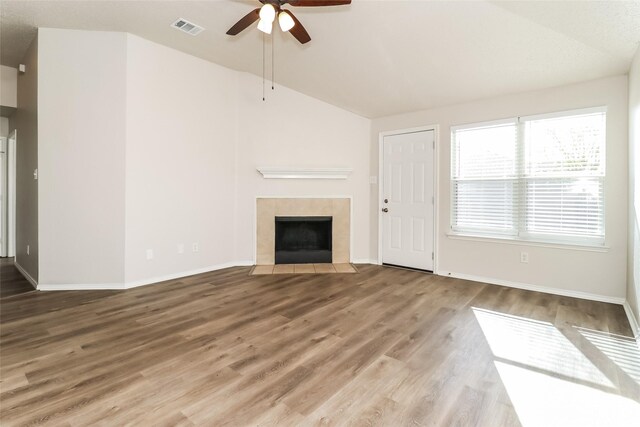 unfurnished living room with a tiled fireplace, ceiling fan, wood-type flooring, and vaulted ceiling