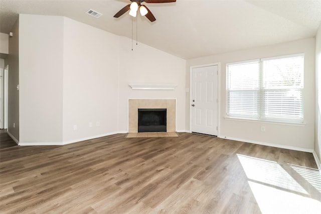 unfurnished living room featuring hardwood / wood-style flooring, a tile fireplace, lofted ceiling, and ceiling fan