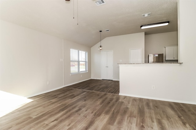 unfurnished living room with vaulted ceiling, dark hardwood / wood-style floors, and a textured ceiling