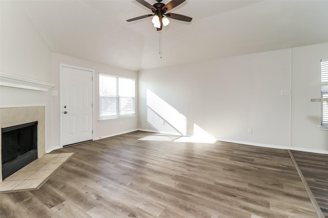 unfurnished living room with wood-type flooring, vaulted ceiling, ceiling fan, and a fireplace