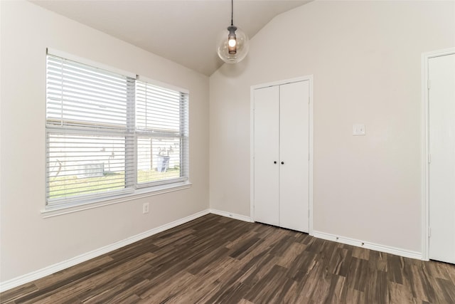 unfurnished bedroom featuring dark wood-type flooring, vaulted ceiling, and a closet