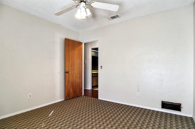 spare room with ceiling fan, dark carpet, and a textured ceiling