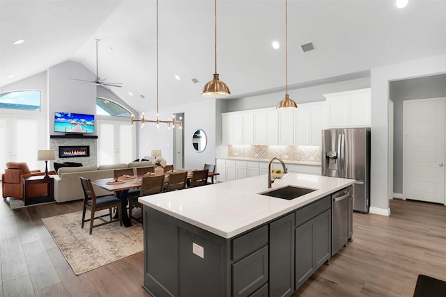 kitchen featuring stainless steel appliances, a kitchen island with sink, backsplash, white cabinetry, and sink