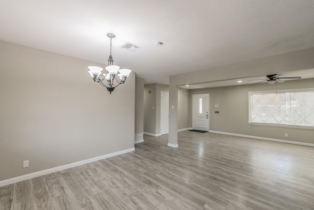 spare room with ceiling fan with notable chandelier and light wood-type flooring