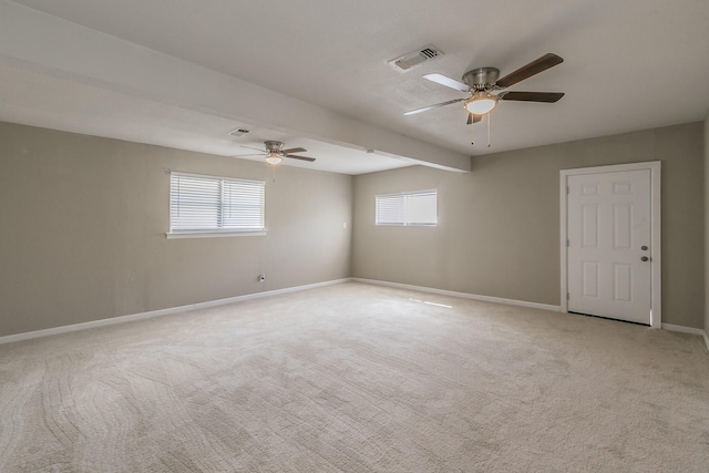 carpeted empty room with ceiling fan and plenty of natural light