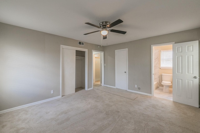 unfurnished bedroom with ceiling fan, light colored carpet, ensuite bathroom, and a closet