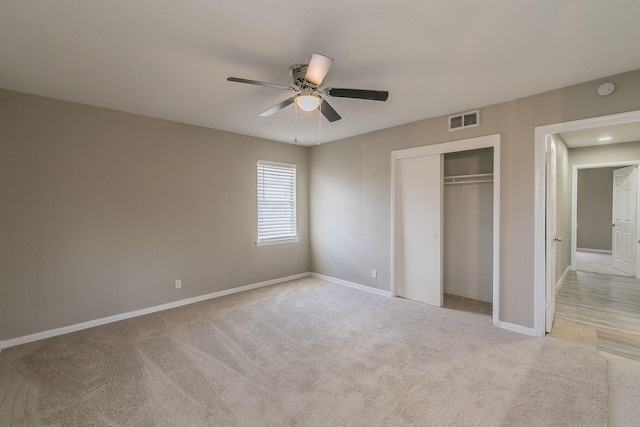 unfurnished bedroom with light colored carpet, a closet, and ceiling fan