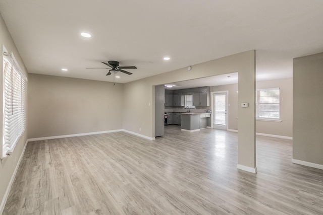 unfurnished living room with ceiling fan, sink, and light hardwood / wood-style flooring