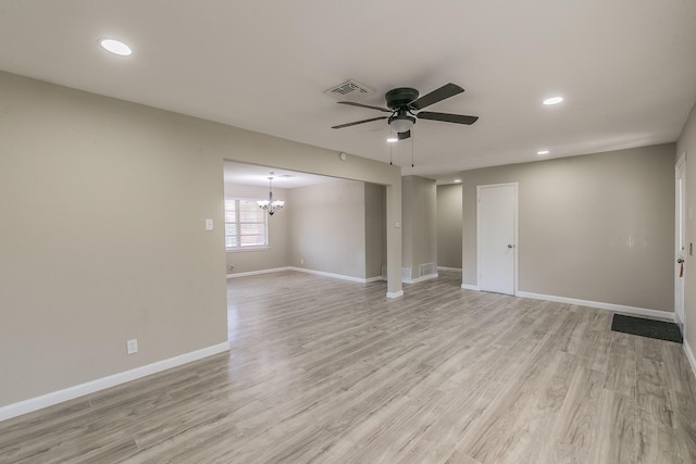 spare room featuring ceiling fan with notable chandelier and light hardwood / wood-style floors