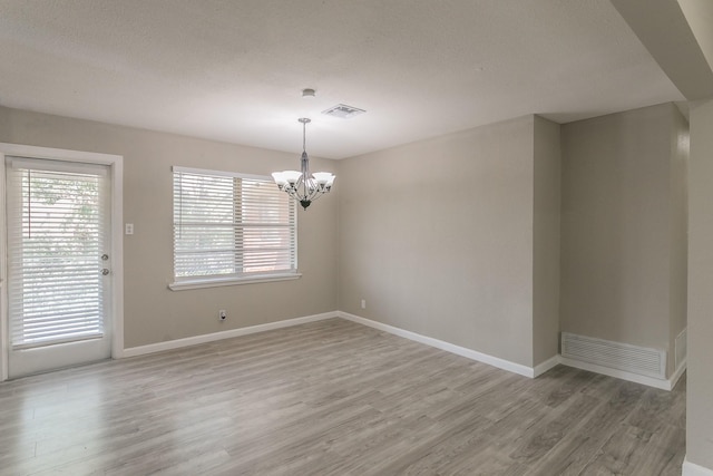 unfurnished room featuring wood-type flooring and a notable chandelier