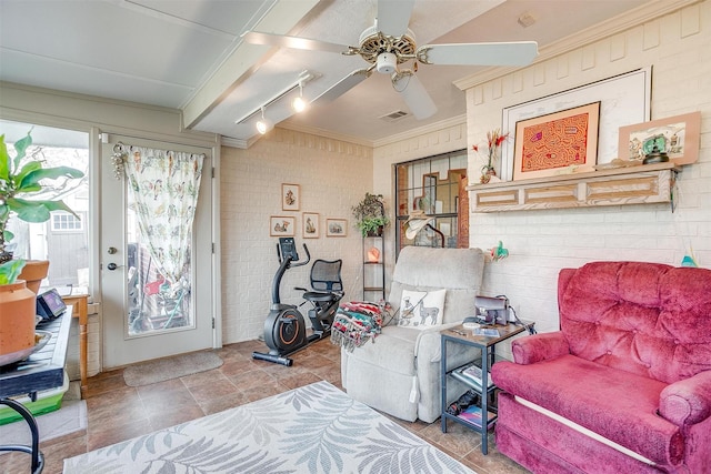 sitting room with track lighting, ceiling fan, and brick wall