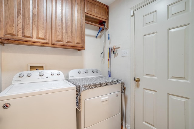 clothes washing area with washer and clothes dryer and cabinets