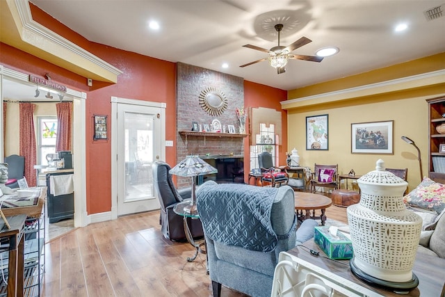 living room featuring a fireplace, ceiling fan, and light hardwood / wood-style flooring