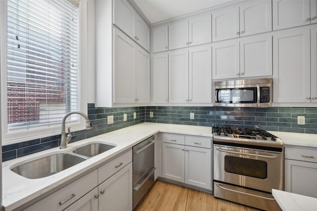 kitchen featuring sink, light wood-type flooring, stainless steel appliances, and tasteful backsplash