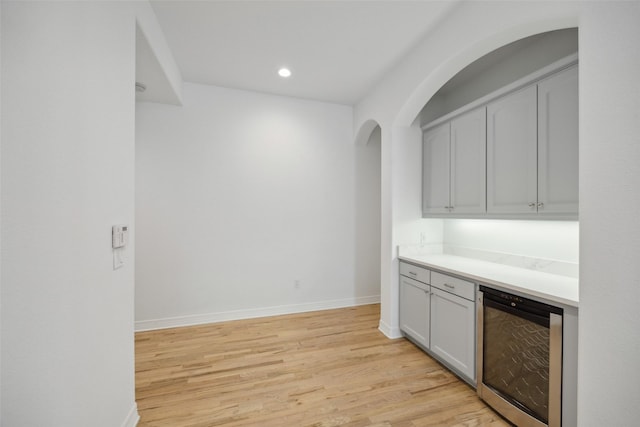 bar with light wood-type flooring and wine cooler