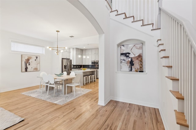 dining space featuring light wood-type flooring and a notable chandelier