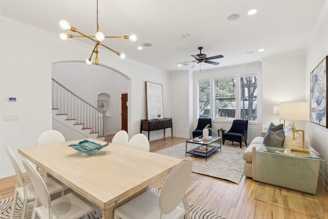 dining area with light wood-type flooring, ceiling fan with notable chandelier, and ornamental molding