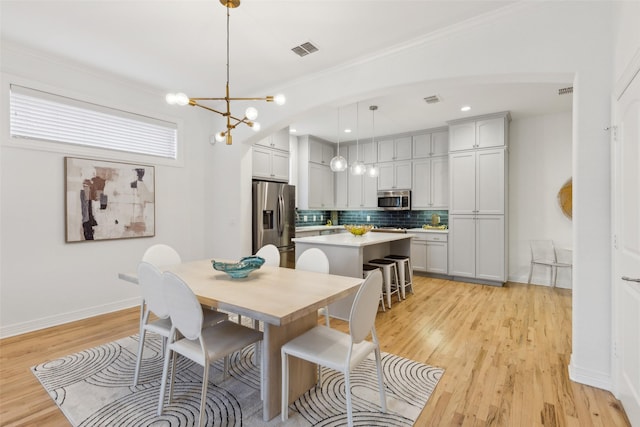 dining area featuring light hardwood / wood-style flooring, a notable chandelier, and crown molding