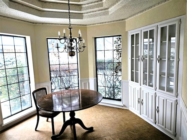 tiled dining area featuring a raised ceiling, crown molding, and a chandelier