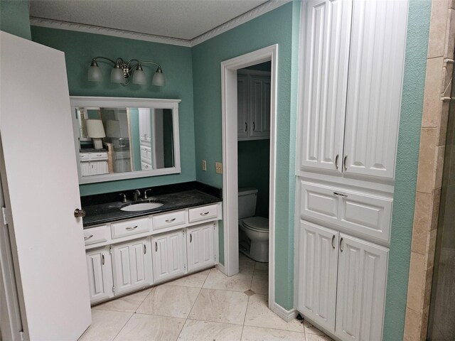 bathroom with tile patterned floors, vanity, toilet, and crown molding