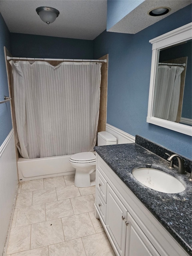 full bathroom featuring vanity, toilet, a textured ceiling, and shower / tub combo with curtain