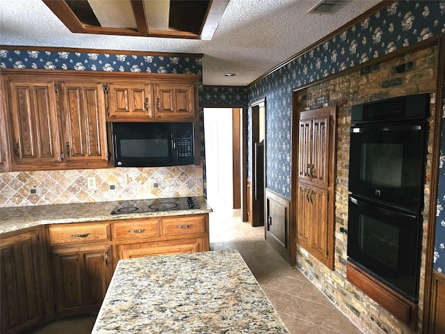 kitchen featuring light stone counters, light tile patterned floors, black appliances, and a textured ceiling