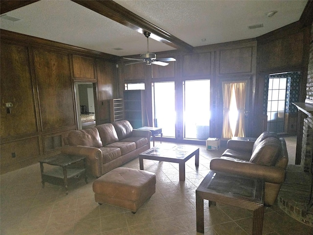 living room featuring wooden walls, beamed ceiling, a textured ceiling, and ceiling fan