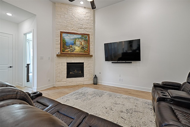 living room with a fireplace, ceiling fan, and light hardwood / wood-style floors