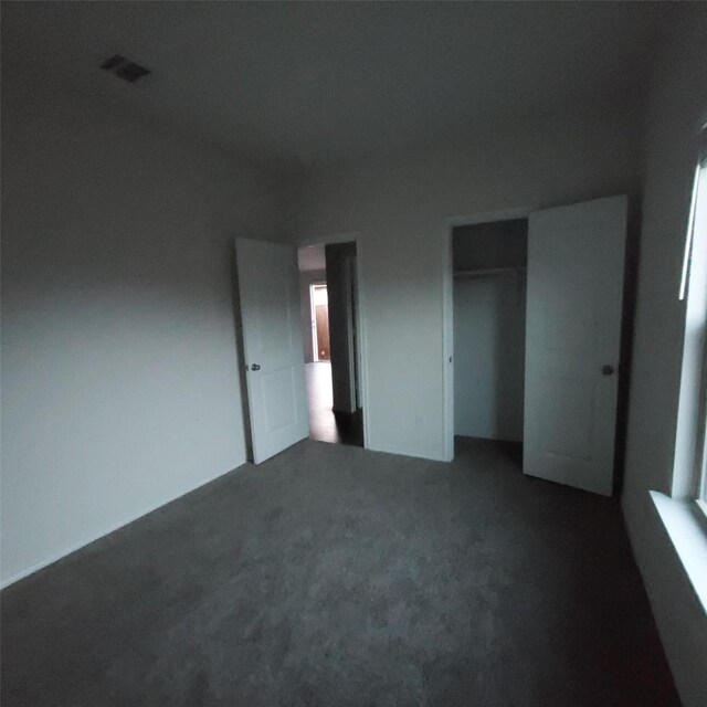 unfurnished bedroom featuring dark carpet and a closet