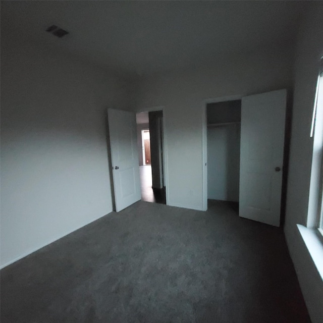 unfurnished bedroom with a closet and dark colored carpet