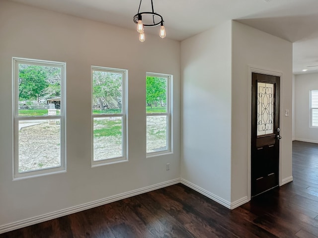 empty room featuring dark wood-type flooring and ceiling fan with notable chandelier