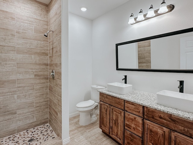 bathroom with vanity, toilet, and tiled shower