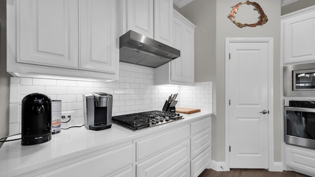 kitchen with backsplash, white cabinetry, stainless steel appliances, and ornamental molding