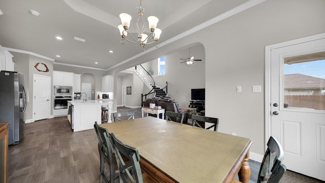 dining room featuring sink, dark wood-type flooring, ceiling fan with notable chandelier, and ornamental molding