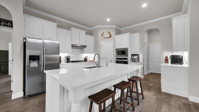 kitchen featuring sink, stainless steel appliances, an island with sink, a kitchen bar, and white cabinets