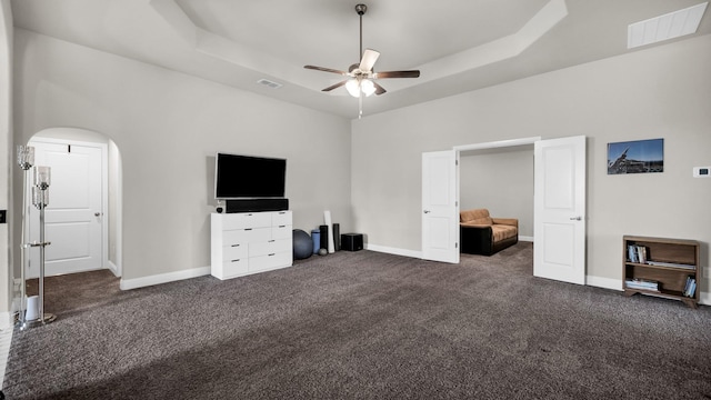 unfurnished bedroom with dark colored carpet, a raised ceiling, and ceiling fan