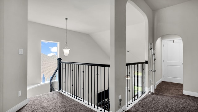 corridor featuring plenty of natural light, dark carpet, and vaulted ceiling