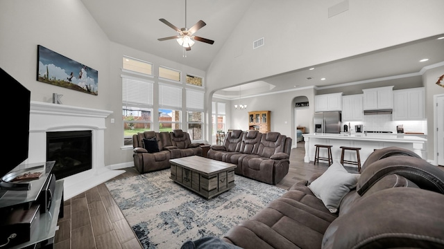 living room with ceiling fan with notable chandelier and a towering ceiling