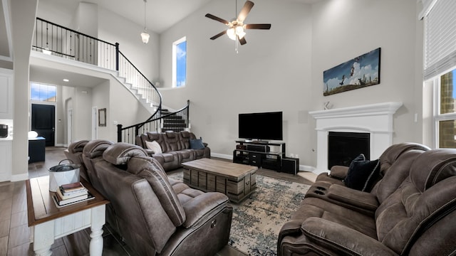 living room featuring hardwood / wood-style floors, a towering ceiling, and ceiling fan