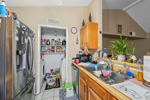 kitchen featuring sink, vaulted ceiling, independent washer and dryer, light tile patterned floors, and appliances with stainless steel finishes