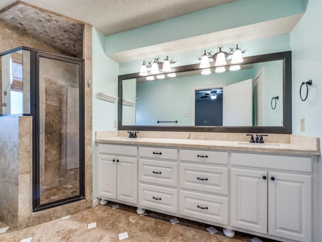 bathroom with a textured ceiling, ceiling fan, vanity, and an enclosed shower