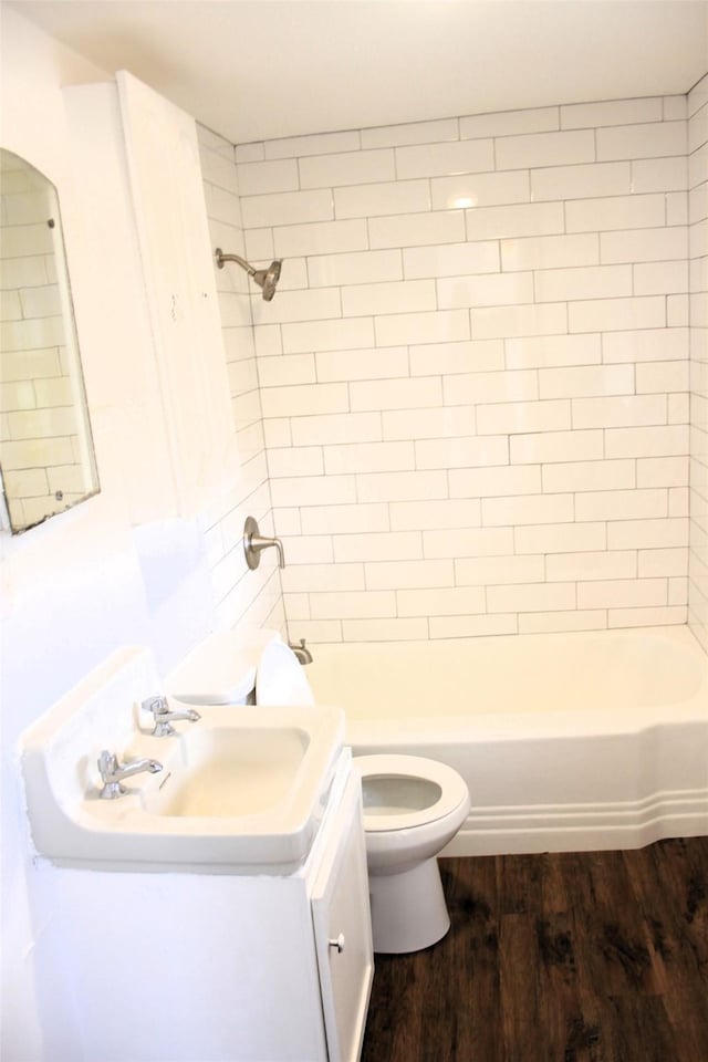 full bathroom featuring tiled shower / bath combo, toilet, wood-type flooring, and vanity