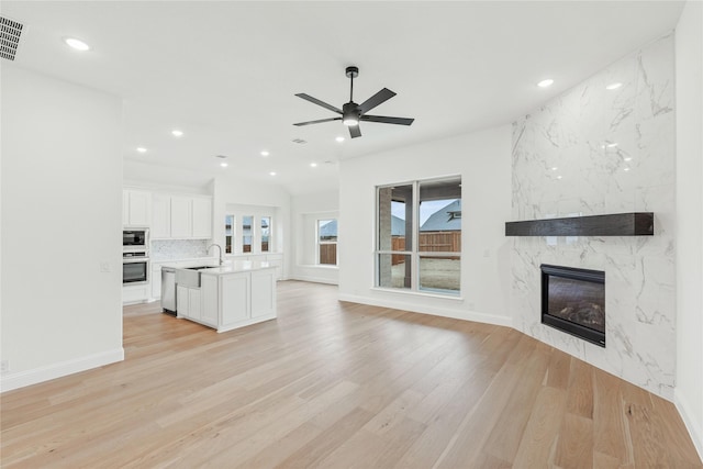 kitchen featuring sink, appliances with stainless steel finishes, custom range hood, an island with sink, and a kitchen bar