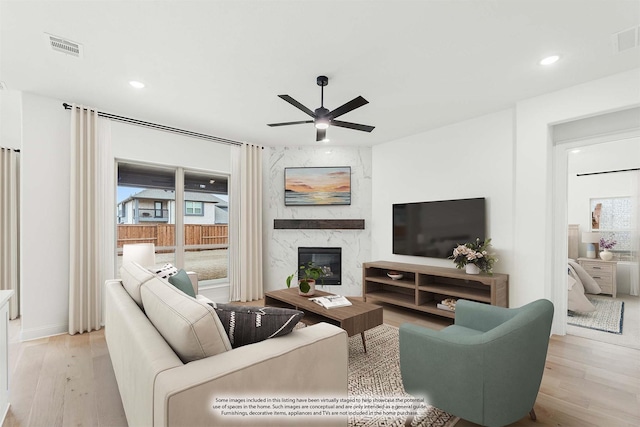 living area featuring ceiling fan, a premium fireplace, light wood-type flooring, and visible vents