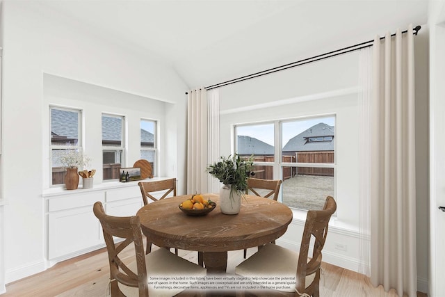 dining area with light wood finished floors, baseboards, and vaulted ceiling