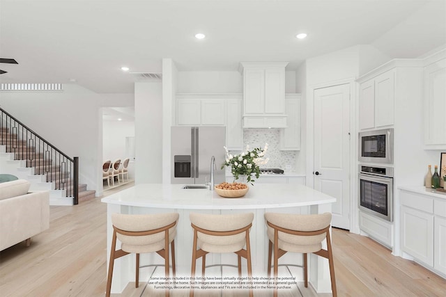 kitchen with light wood-type flooring, visible vents, appliances with stainless steel finishes, and a breakfast bar