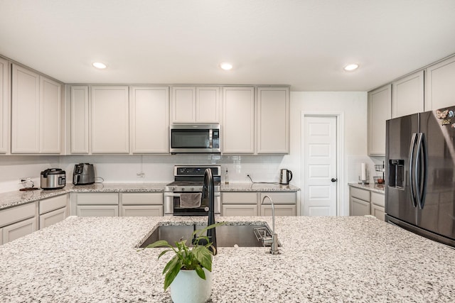 kitchen featuring sink, backsplash, light stone counters, and stainless steel appliances