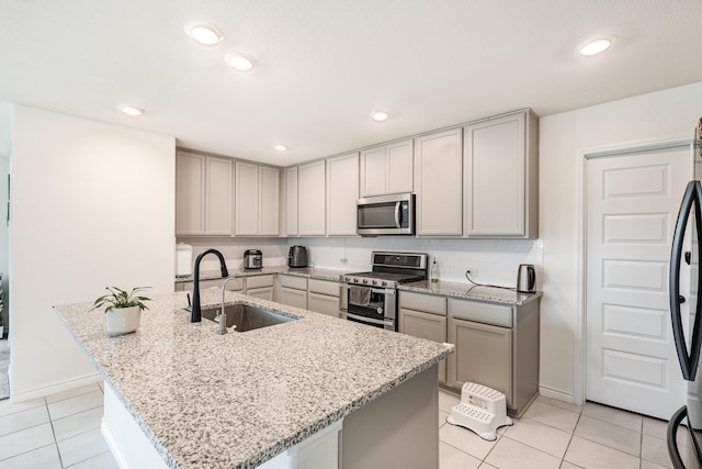 kitchen with light stone counters, sink, light tile patterned floors, and stainless steel appliances